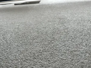 Nahaufnahme einer frisch verputzten Außenwand mit grobkörniger Struktur in hellem Grau.