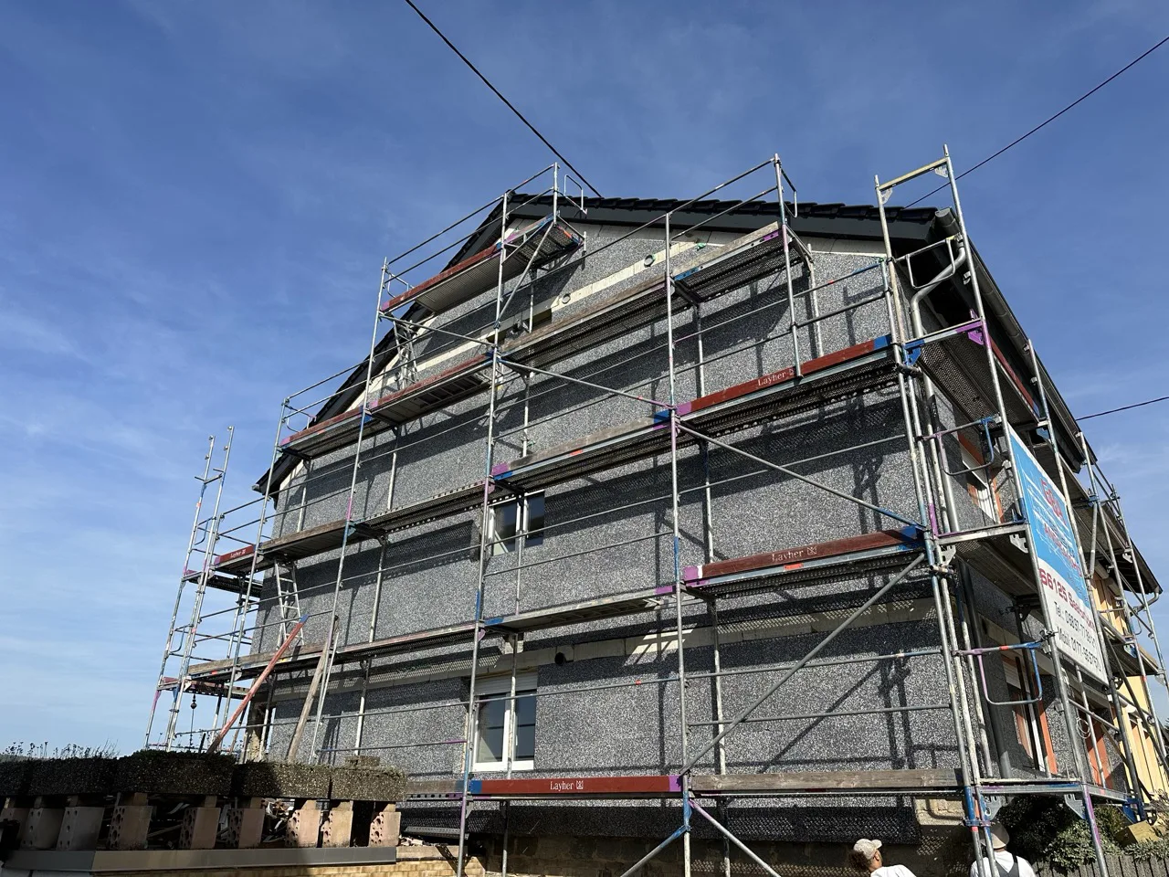 Ein mehrstöckiges Wohnhaus mit Gerüst an der Fassade, auf dem ein neues Wärmedämmverbundsystem angebracht wird.